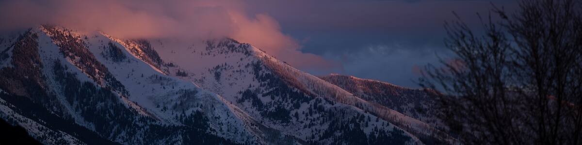 Snowy Utah mountains glow under dramatic purple-pink sunset sky