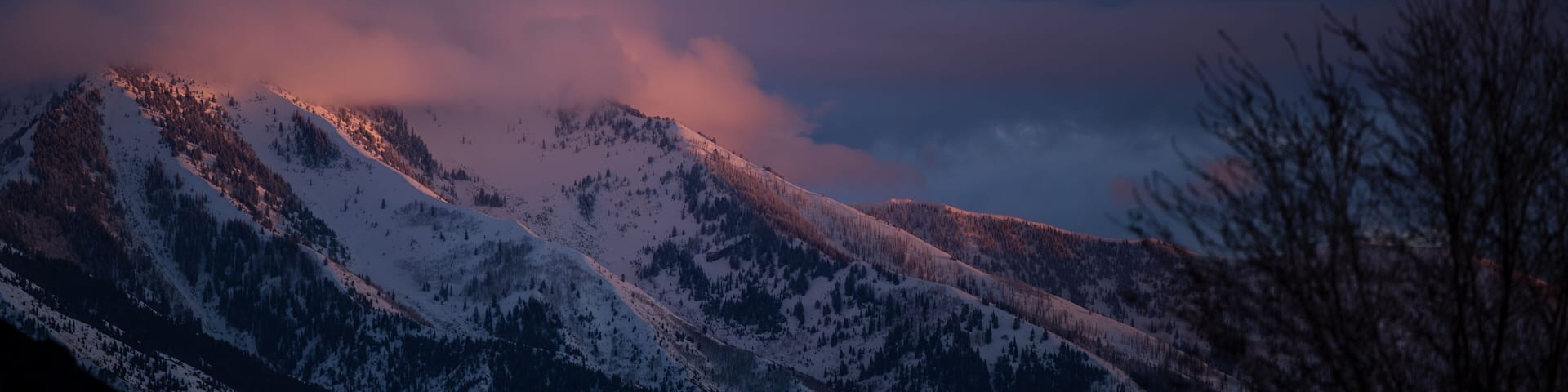 Snowy Utah mountains glow under dramatic purple-pink sunset sky