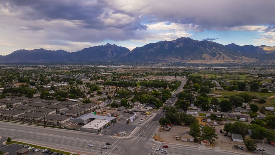 A town with a mountain range in the background, a main road, and several buildings.