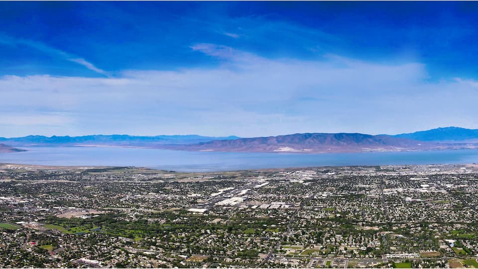 A coastal city with mountains in the background and a large body of water.