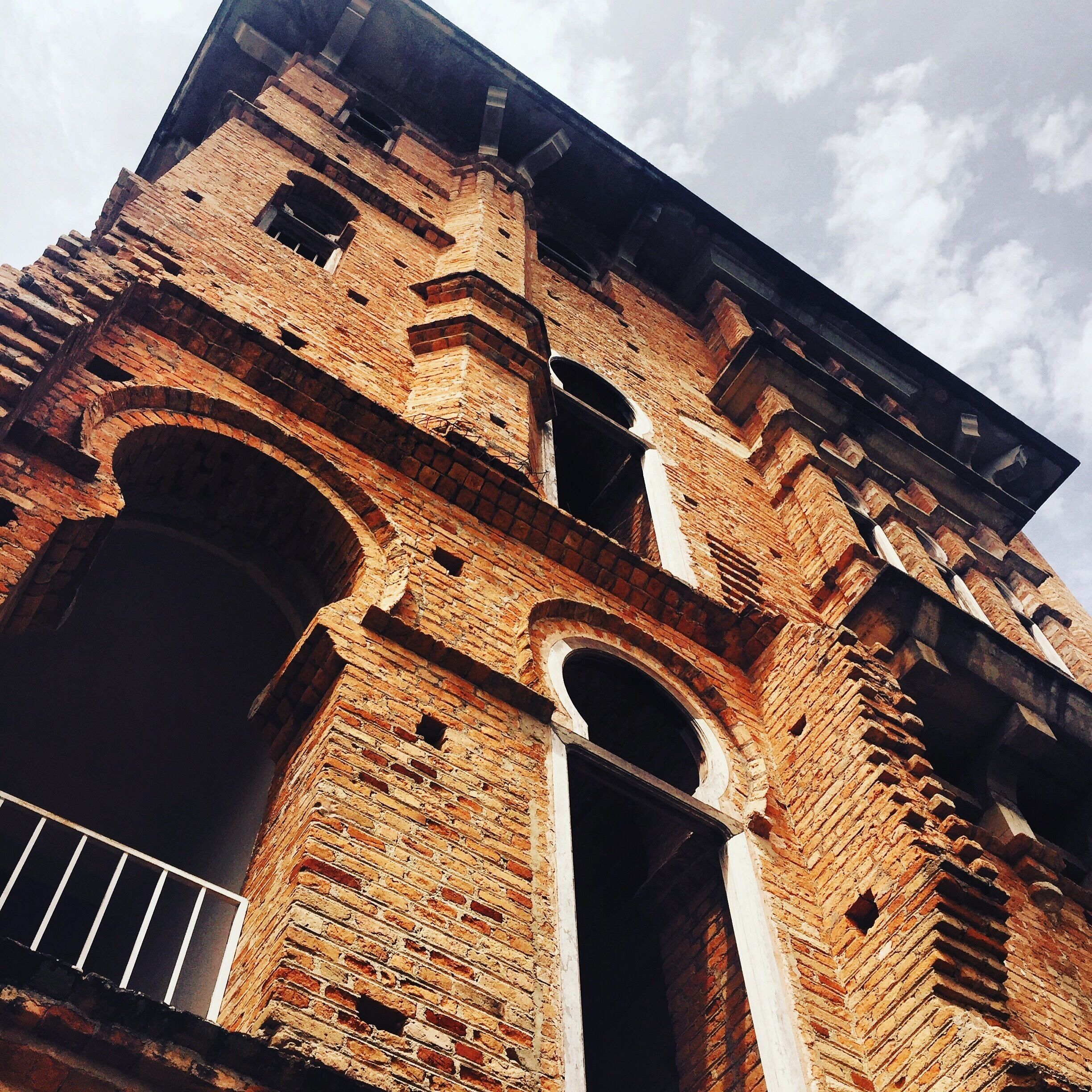 A large brick building with multiple arches and a balcony.