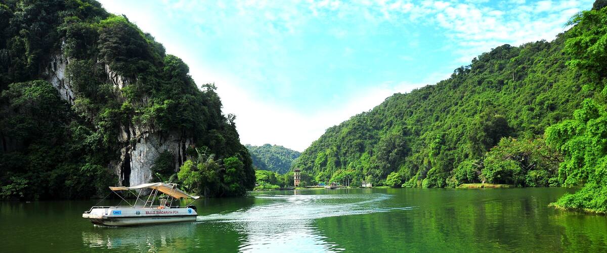 A boat on a river surrounded by lush green hills.