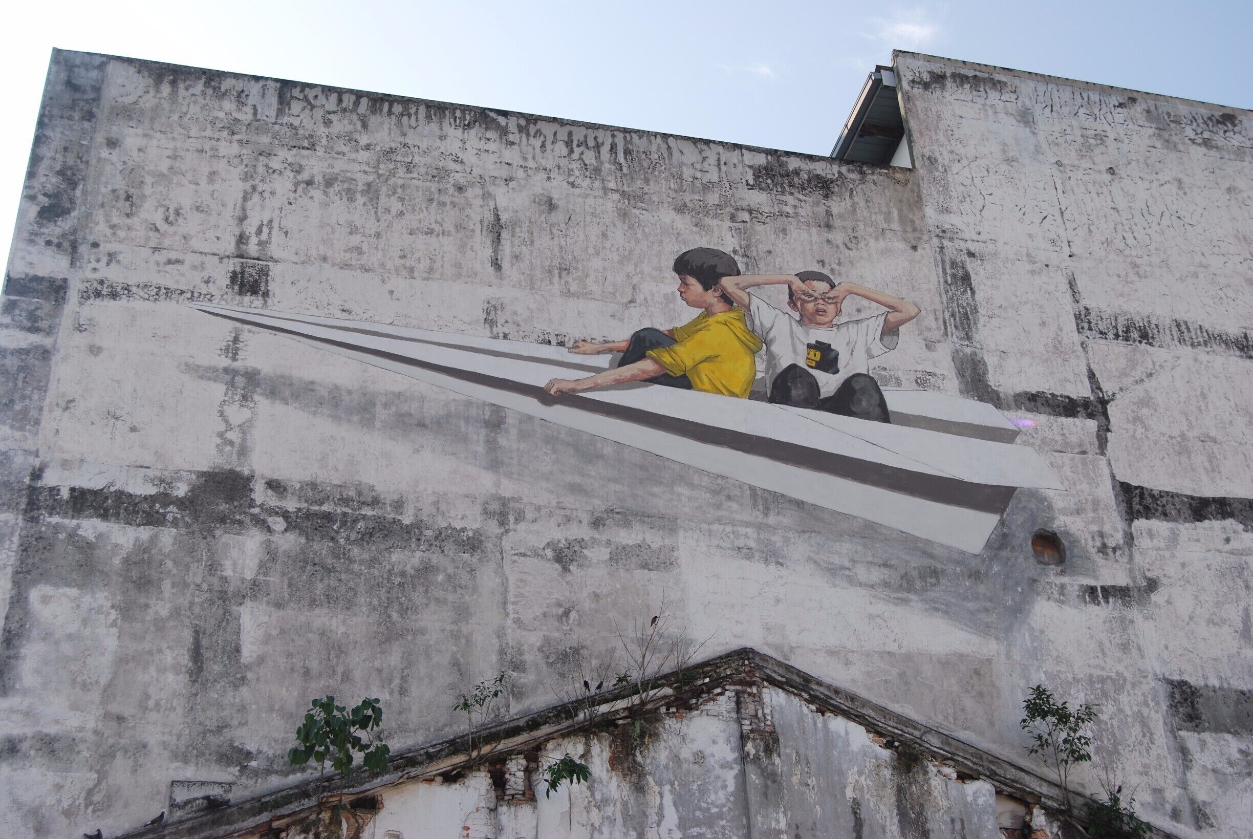 A mural of two children on a concrete wall.