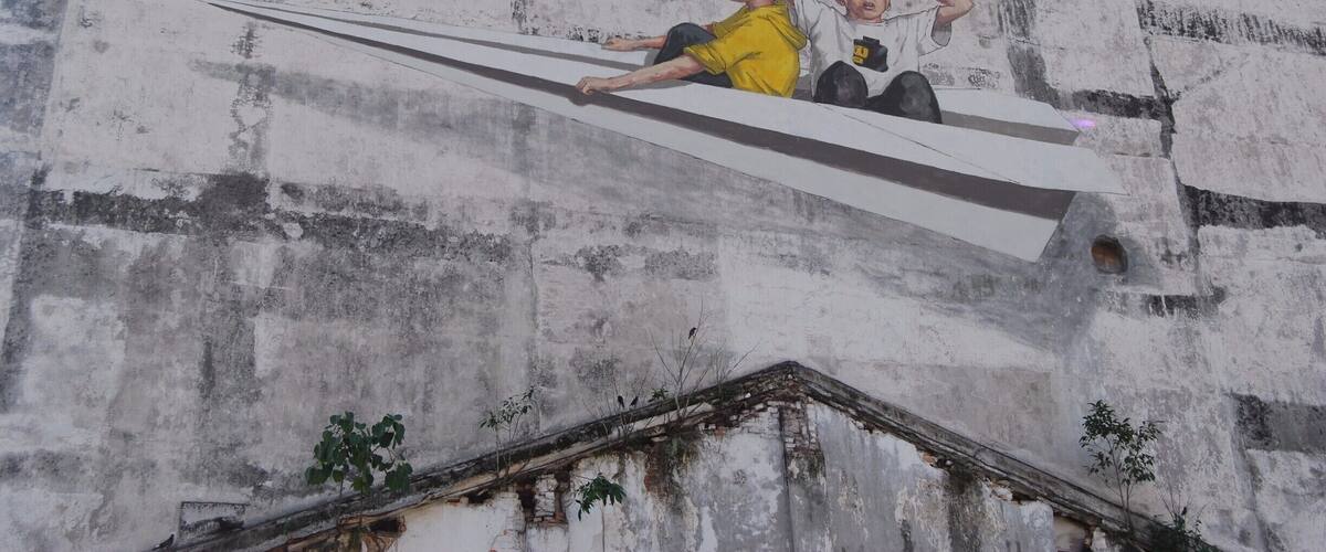 A mural of two children on a concrete wall.