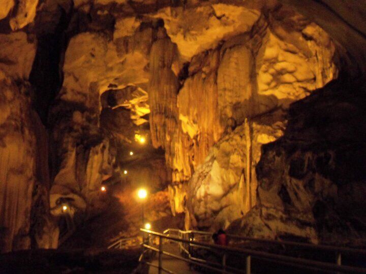 A cave interior with rock formations and a metal railing.