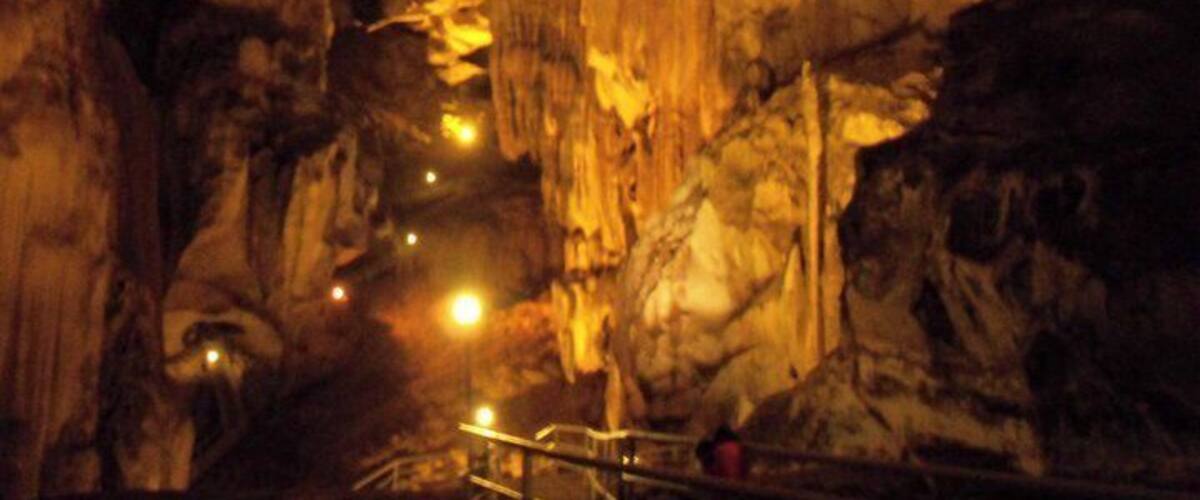 A cave interior with rock formations and a metal railing.