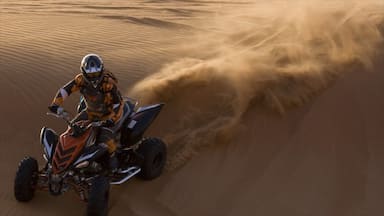 Uma pessoa a andar de quadriciclo numa duna de areia.