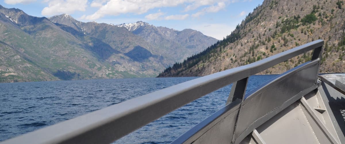 A boat on a calm lake with mountains in the background.