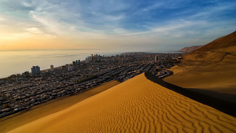 Stunning view to sand dunes, ocean and Iquique city at sunset