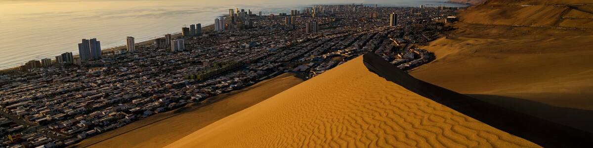 Stunning view to sand dunes, ocean and Iquique city at sunset