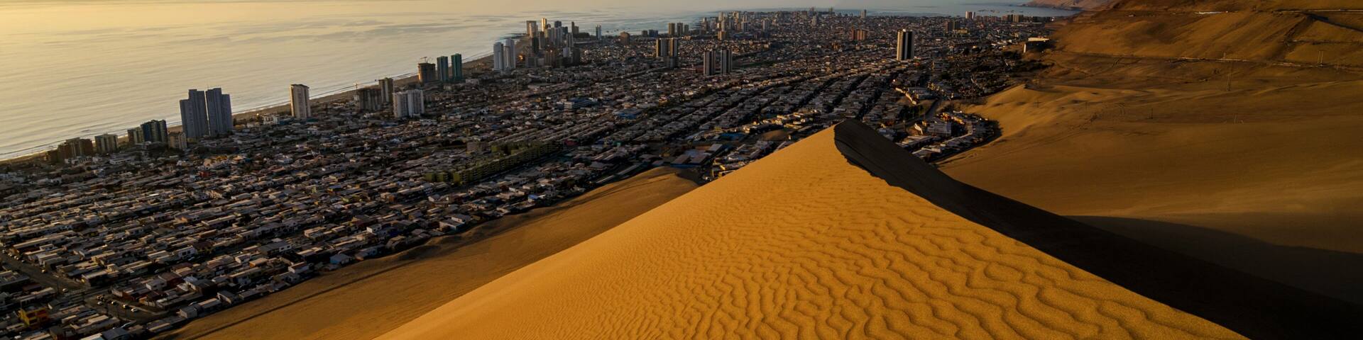 Stunning view to sand dunes, ocean and Iquique city at sunset