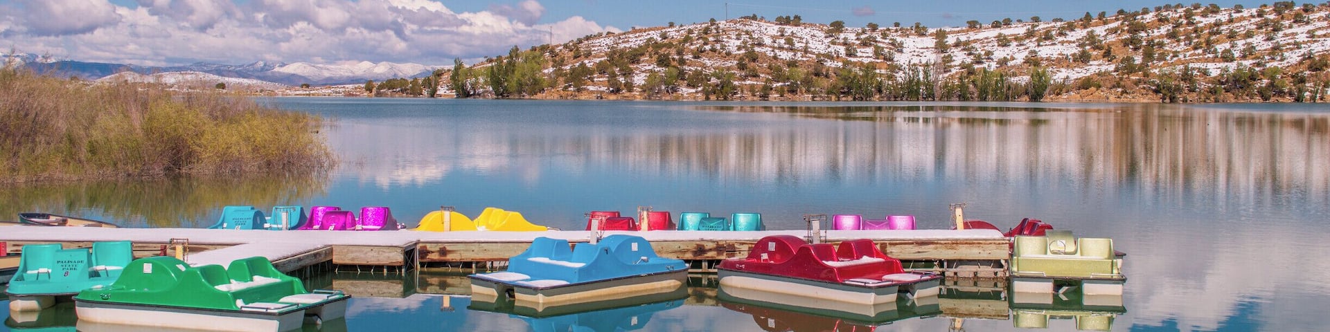Colorful paddleboats on crystal blue Palisade Lake in Paslisade State Park. We were there in May of 2014, and woke up on Mother's Day to a surprise 9 inches of snow! It had mostly melted by the next day but still provided a pretty contrast to the bright blue sky. This state park offers fishing, camping, golfing, OHV trails, and boat rentals. #utah #palisadelake #snow #lake