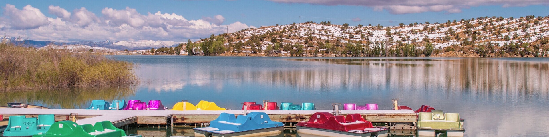 Colorful paddleboats on crystal blue Palisade Lake in Paslisade State Park. We were there in May of 2014, and woke up on Mother's Day to a surprise 9 inches of snow! It had mostly melted by the next day but still provided a pretty contrast to the bright blue sky. This state park offers fishing, camping, golfing, OHV trails, and boat rentals. #utah #palisadelake #snow #lake