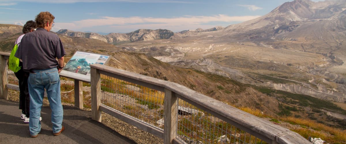 A mountainous landscape with a wooden viewing platform and a sign.