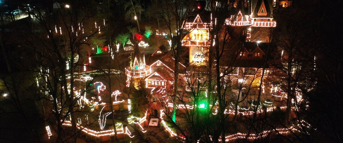 A nighttime view of a residential area with houses adorned with holiday lights.