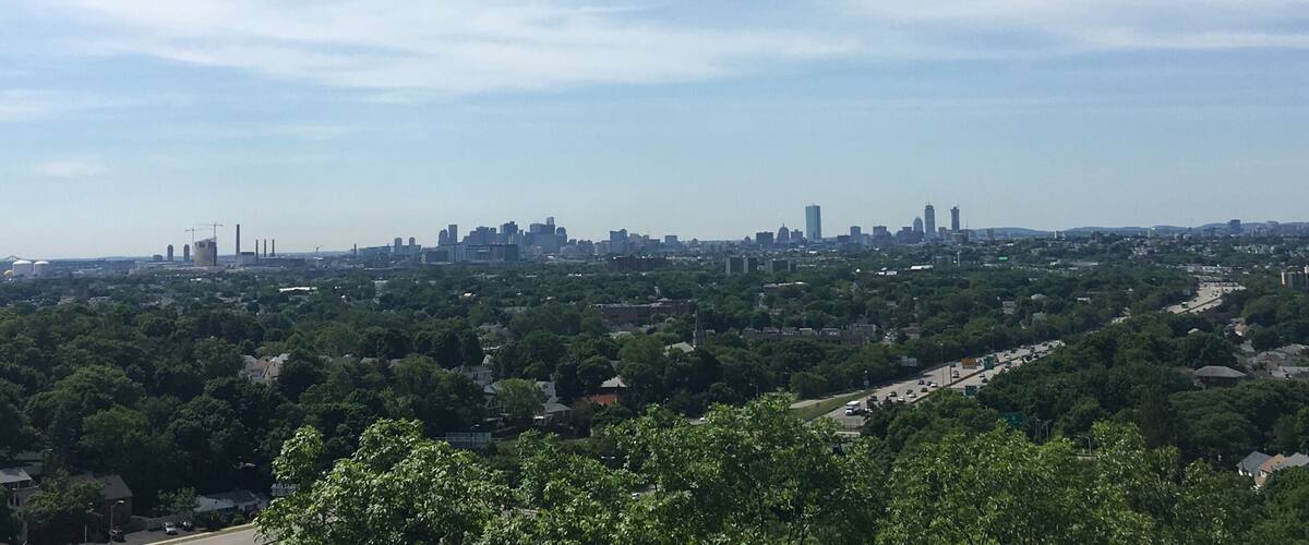 A city skyline with industrial buildings and a highway.