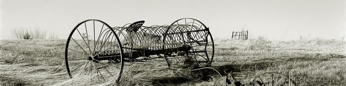 A vintage tractor and a wireframe structure in a grassy field.