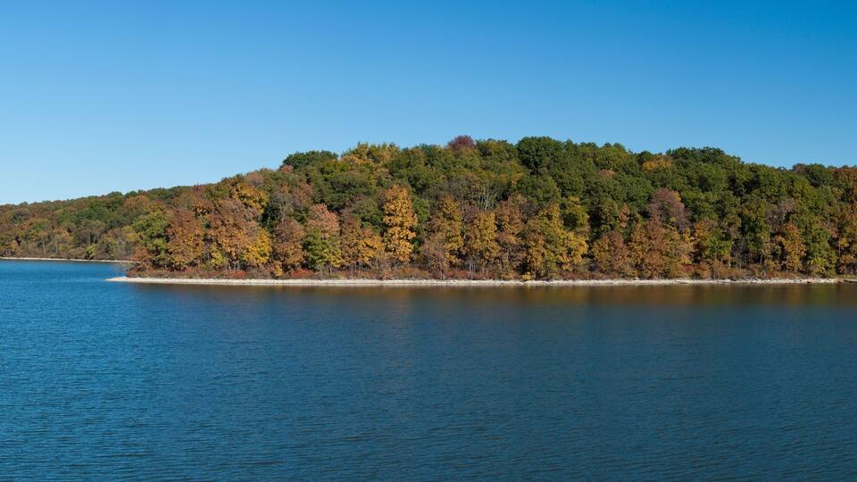 A calm lake with a forested island in the distance.