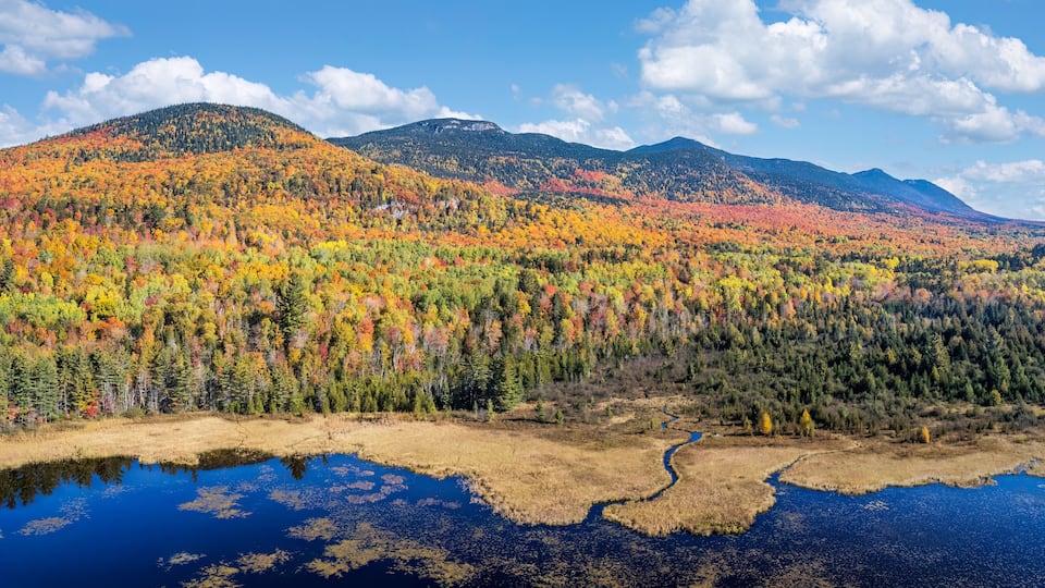 A mountainous landscape with autumn foliage and a lake.