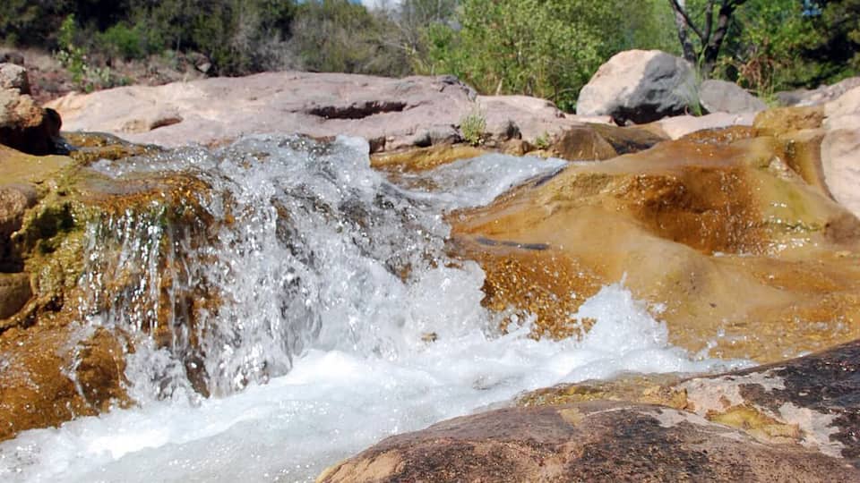 A natural waterfall flowing over rocks in a forested area.