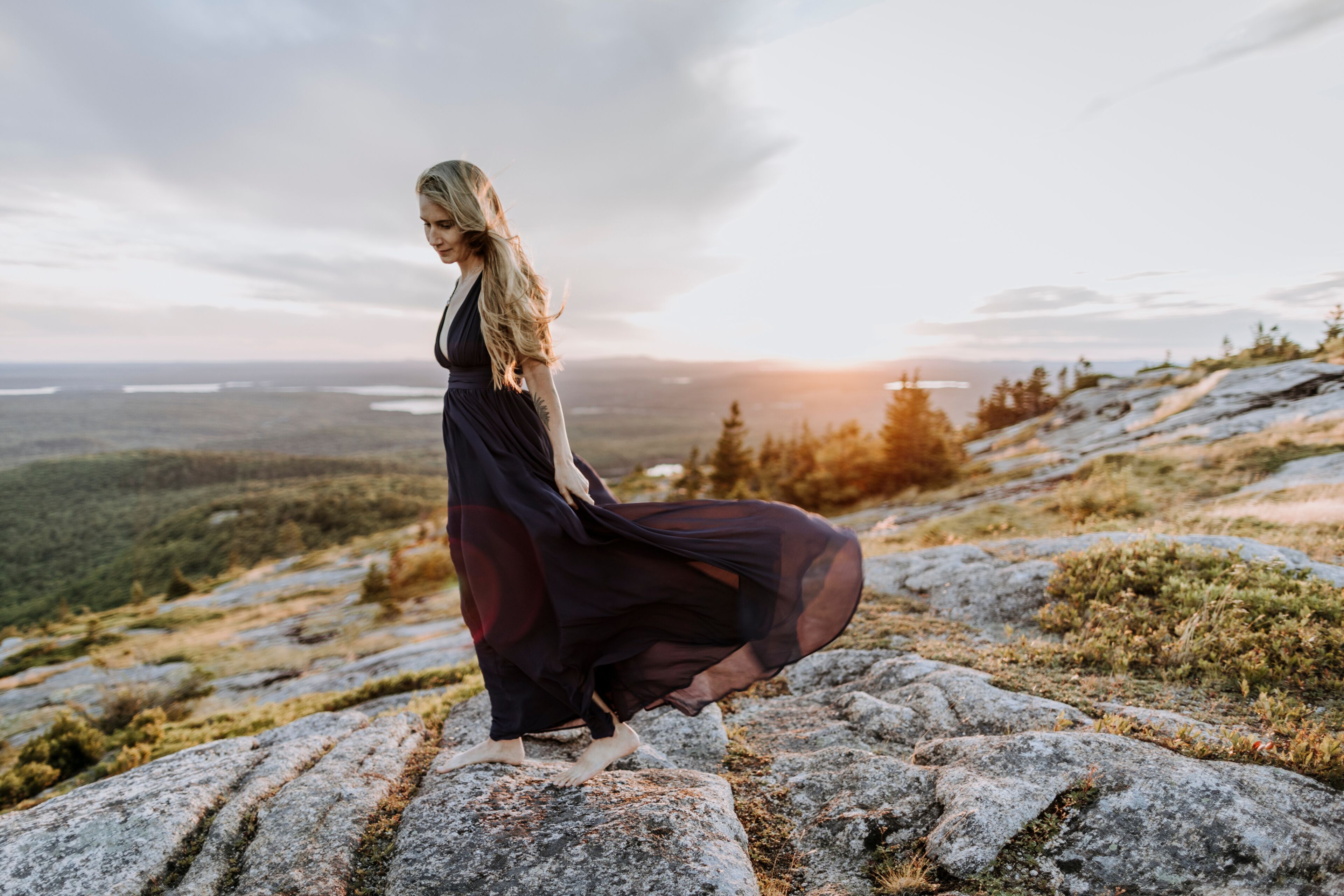 A person standing on a rocky outcrop with a vast landscape in the background.