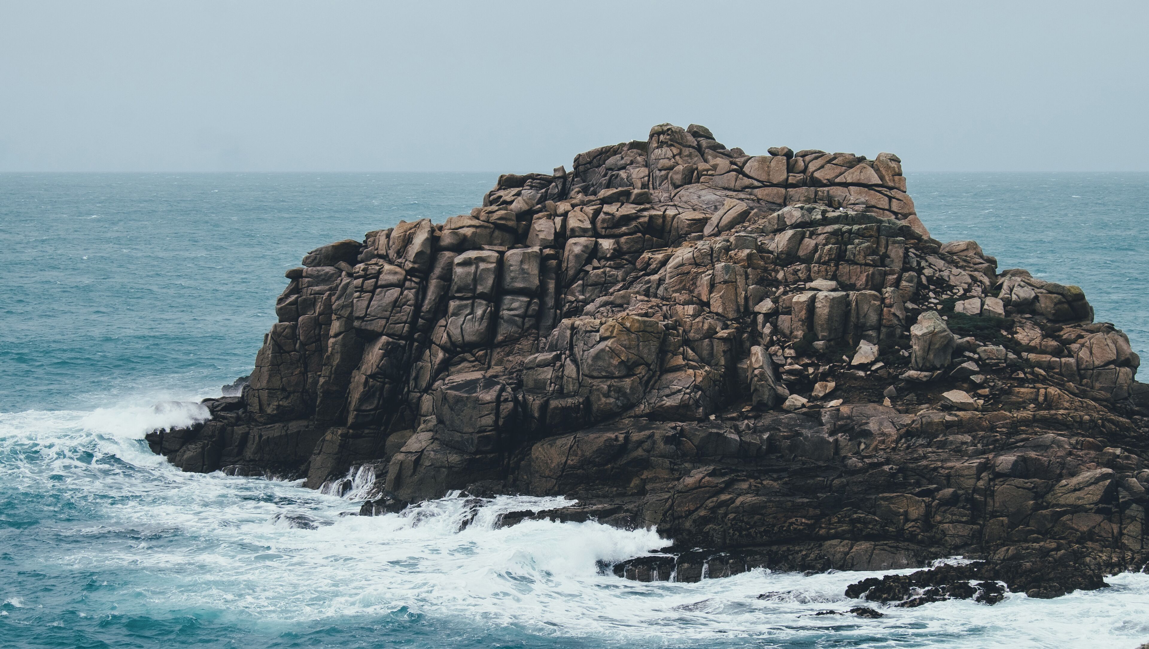 A rocky coastal formation with waves crashing against it.