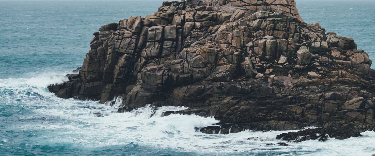 A rocky coastal formation with waves crashing against it.