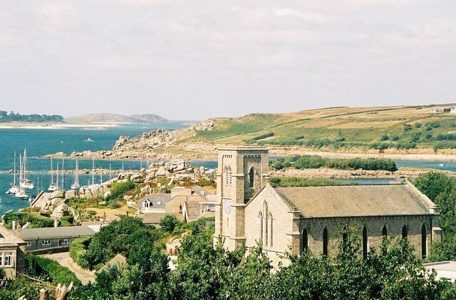 A coastal town with a prominent church, marina, and hilly landscape.