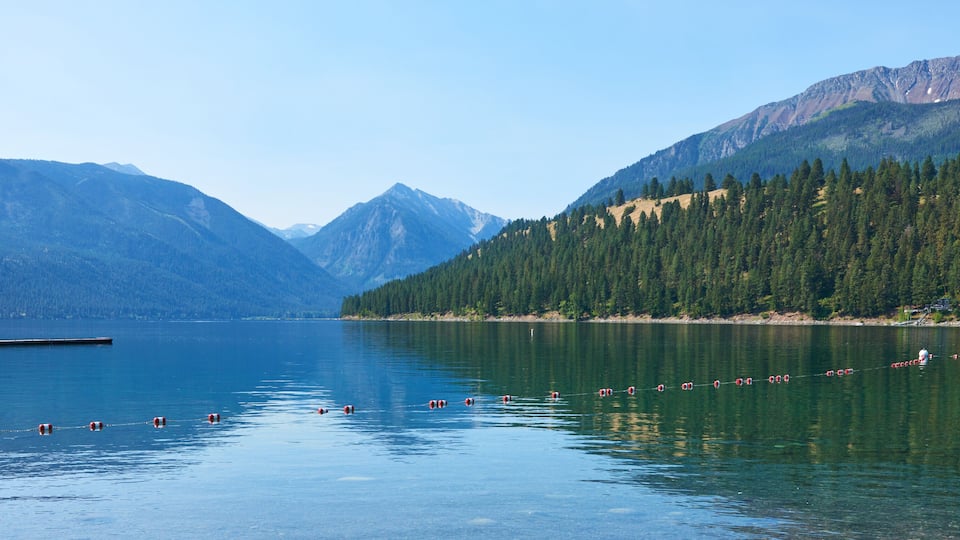 A calm lake surrounded by mountains and dense forests.