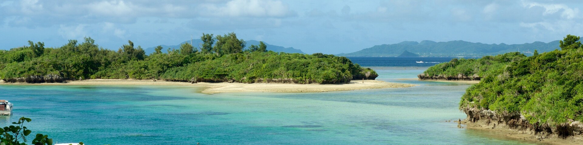 Una isla tropical con aguas turquesas cristalinas, playas de arena y exuberante vegetación.