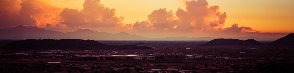 A panorama of a dramatic sunset over the desert with buildings in the foreground