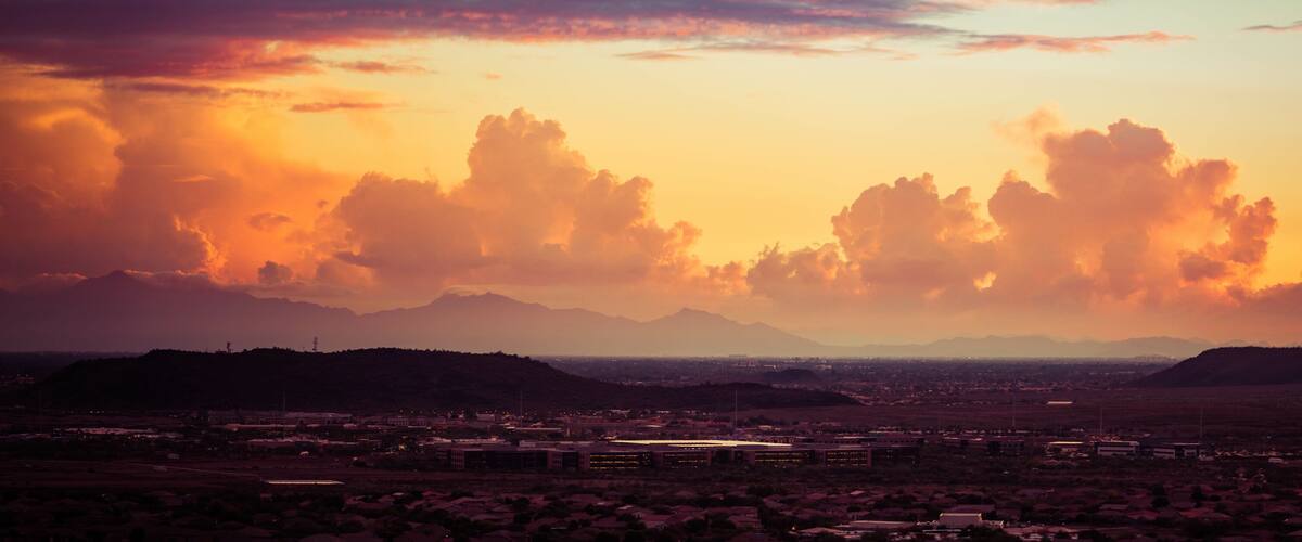 A cityscape at sunset with mountains in the background.