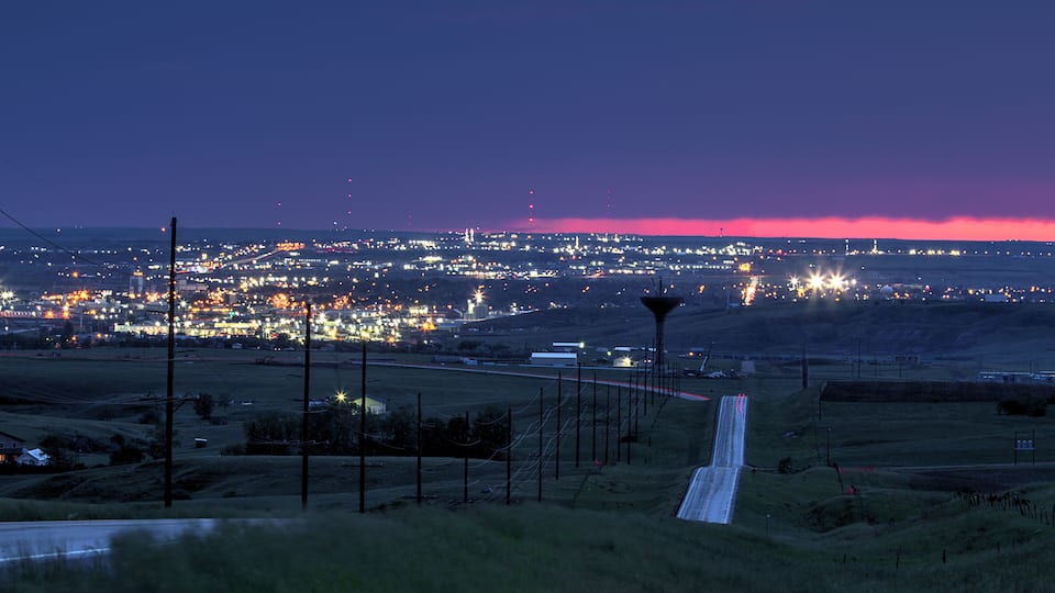 A nighttime view of a city with a runway extending into the distance.
