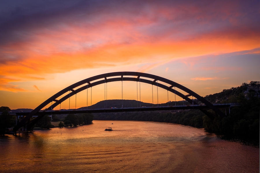 Austin, Texas - Colorful sunset over the Pennybacker Bridge (360 Bridge) spanning Lake Austin. Scenic view of the iconic arch bridge, Texas Hill Country cliffs, and Capital of Texas Highway.