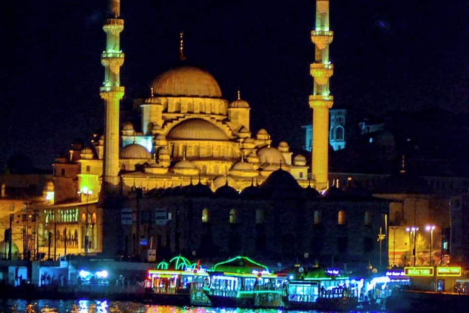 Una mesquita amb dues minarets i una cúpula gran, il·luminada durant la nit.