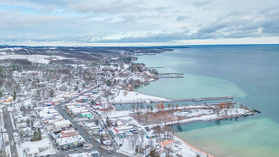A winter town with a waterfront, snow-covered streets, and a pier extending into the water.