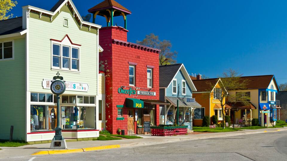 A street lined with colorful buildings, including a green building with a clock and a red building with a sign that reads "Okeefee's Firehouse Pub."