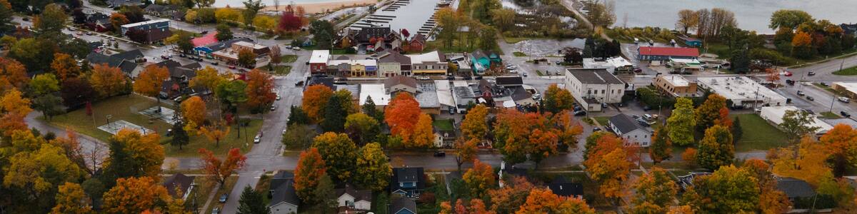 Eine Vogelperspektive einer Küstenstadt mit Herbstlaub, einem Yachthafen und einer Brücke, die zum Festland führt.