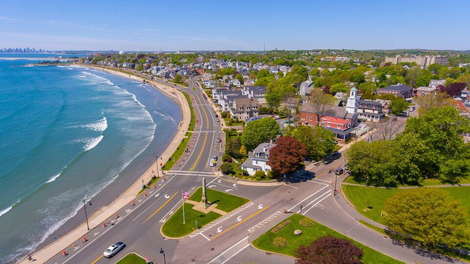 A coastal town with a beach, roads, and residential buildings.
