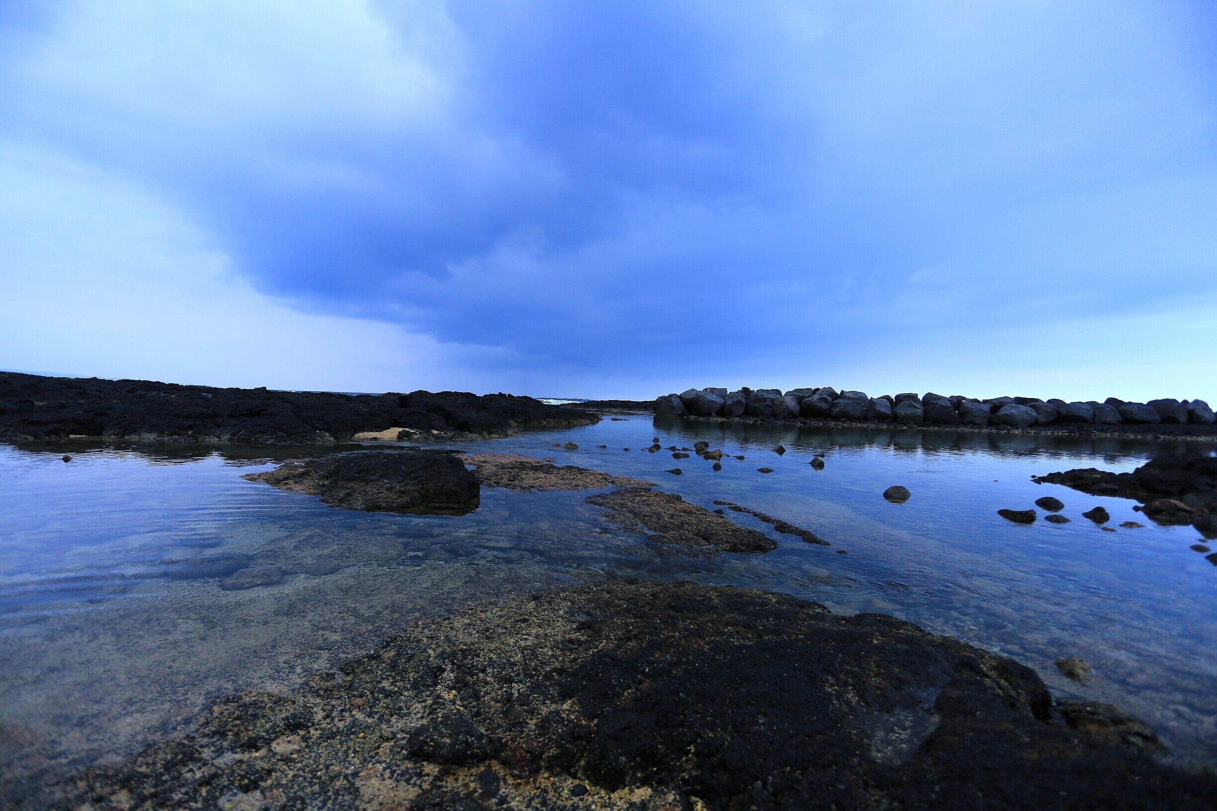 #blue
Located just south of downtown Hilo on the Big Island’s east shore, Onekahakaha Beach Park is the ideal beach for families with small children and for tidepooling. There is a sand-bottomed cove that is separated from the open ocean by a boulder break, so the nearshore waters are shallow and free of currents or wave action. Also, lifeguards are on duty year-round.
Surrounding the cove are a few tide pools, which are sometimes visited by sea turtles. The largest one of them is home to a large population of sea urchins, as well as sea cucumbers, brittle stars, cone shells, sea urchins and sea anemones. However, this pool is not as children-friendly as it has a rockier and deeper bottom and is not protected by the breakwater. Also, it is subject to currents.
The water is crystal clear and shallow behind the boulder wall so its a great place to watch beautuful waves hit the rocks. We did see at least two water turtles wading here. The kids loved it!