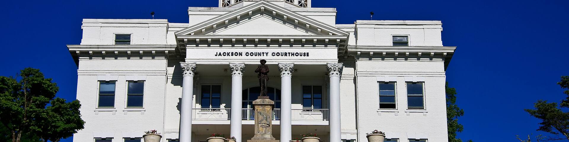 A white courthouse with a clock tower, columns, and a dome.