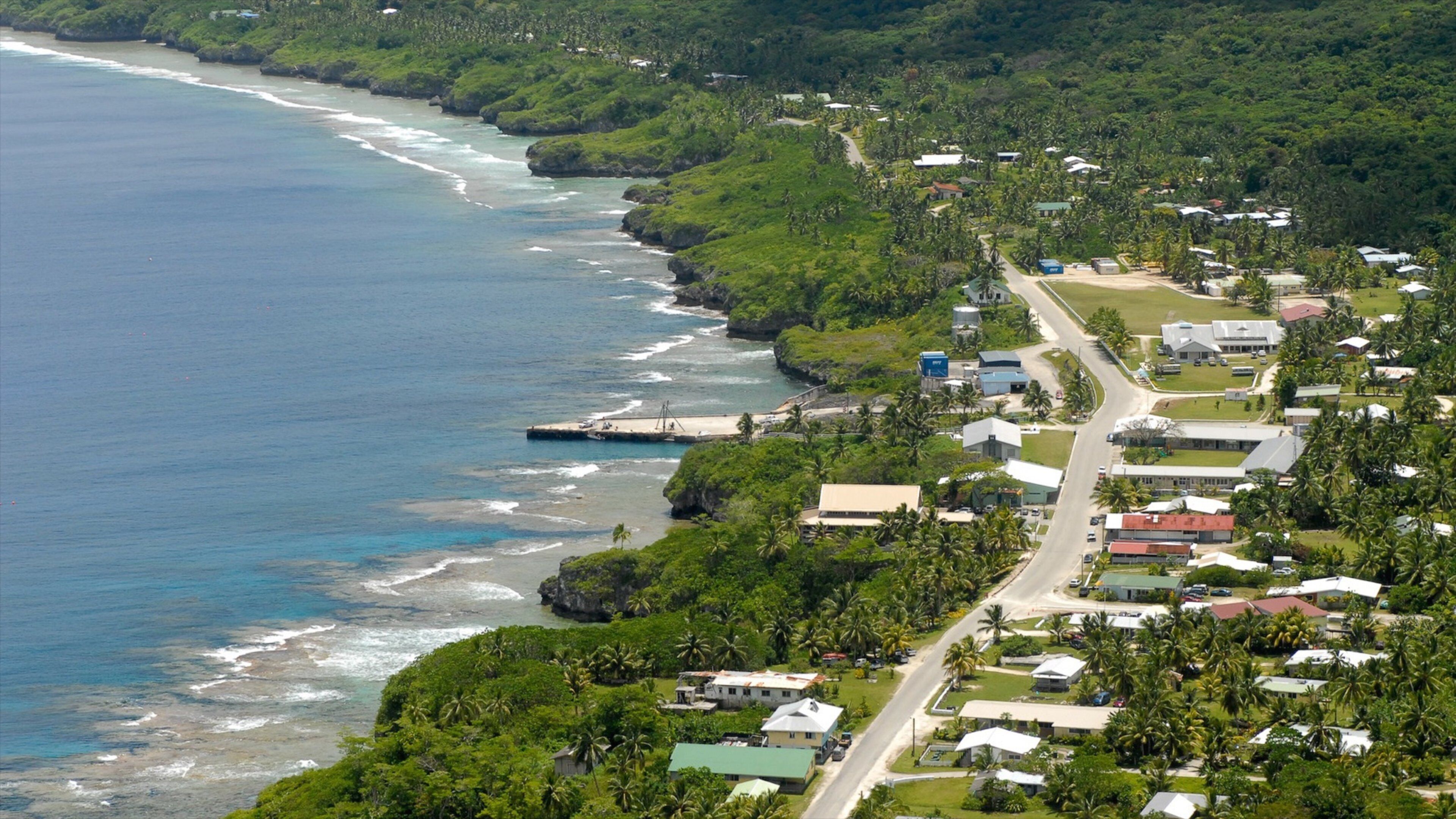 A coastal town with a beach, houses, and lush greenery.