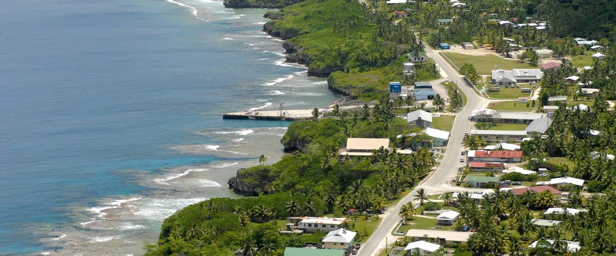 A coastal town with a beach, houses, and lush greenery.