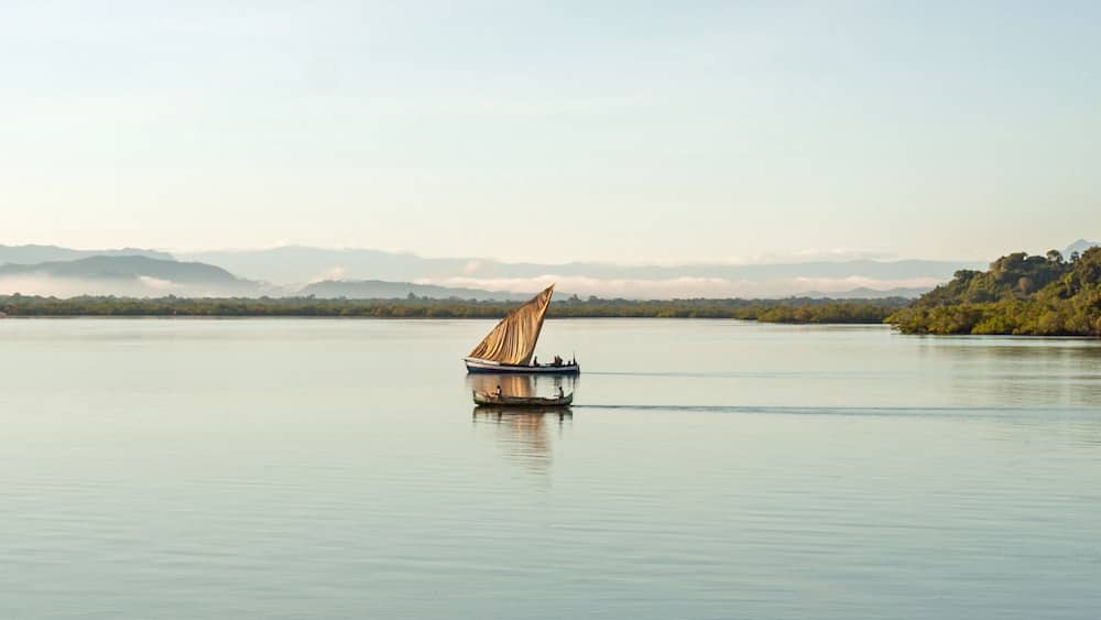Nosy Be, Madagascar: traditional sailing boat and canoe sail out on the Indian Ocean from Port Ankify, Ambanja district, Northern Madagascar.