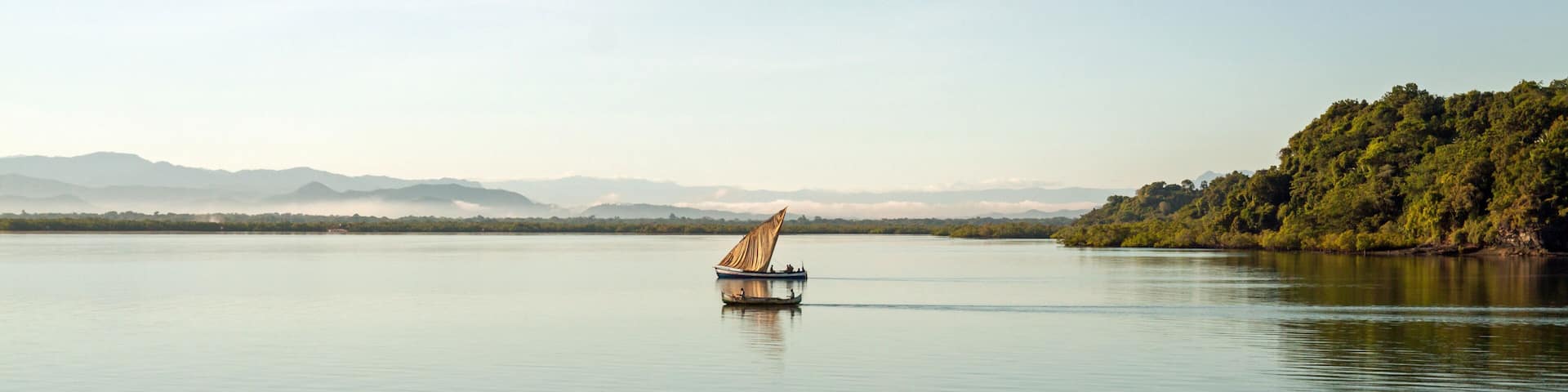 Nosy Be, Madagascar: traditional sailing boat and canoe sail out on the Indian Ocean from Port Ankify, Ambanja district, Northern Madagascar.