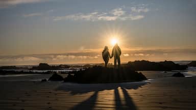 Couple holding hands, watching the sunrise at a rocky beach. Catlins, South Island.