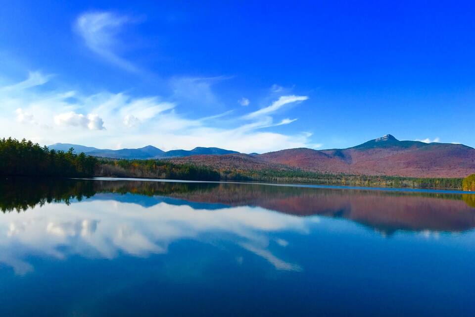 Un lac paisible où se reflètent les montagnes et un ciel dégagé.