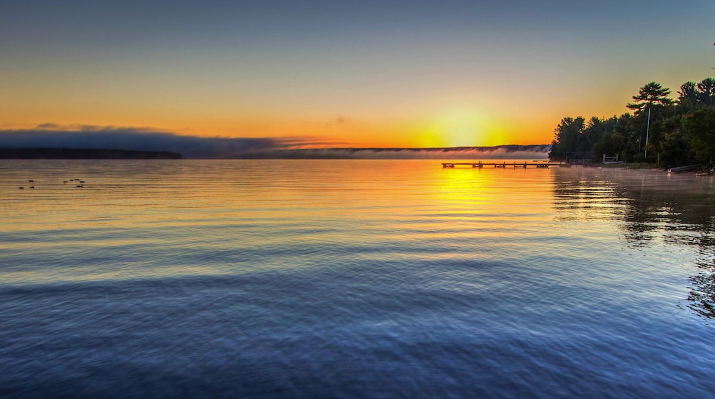 Foggy Summer Lake Sunrise Panorama. Sunrise over Lake Superior on a foggy summer morning with a small wooden dock at the horizon.