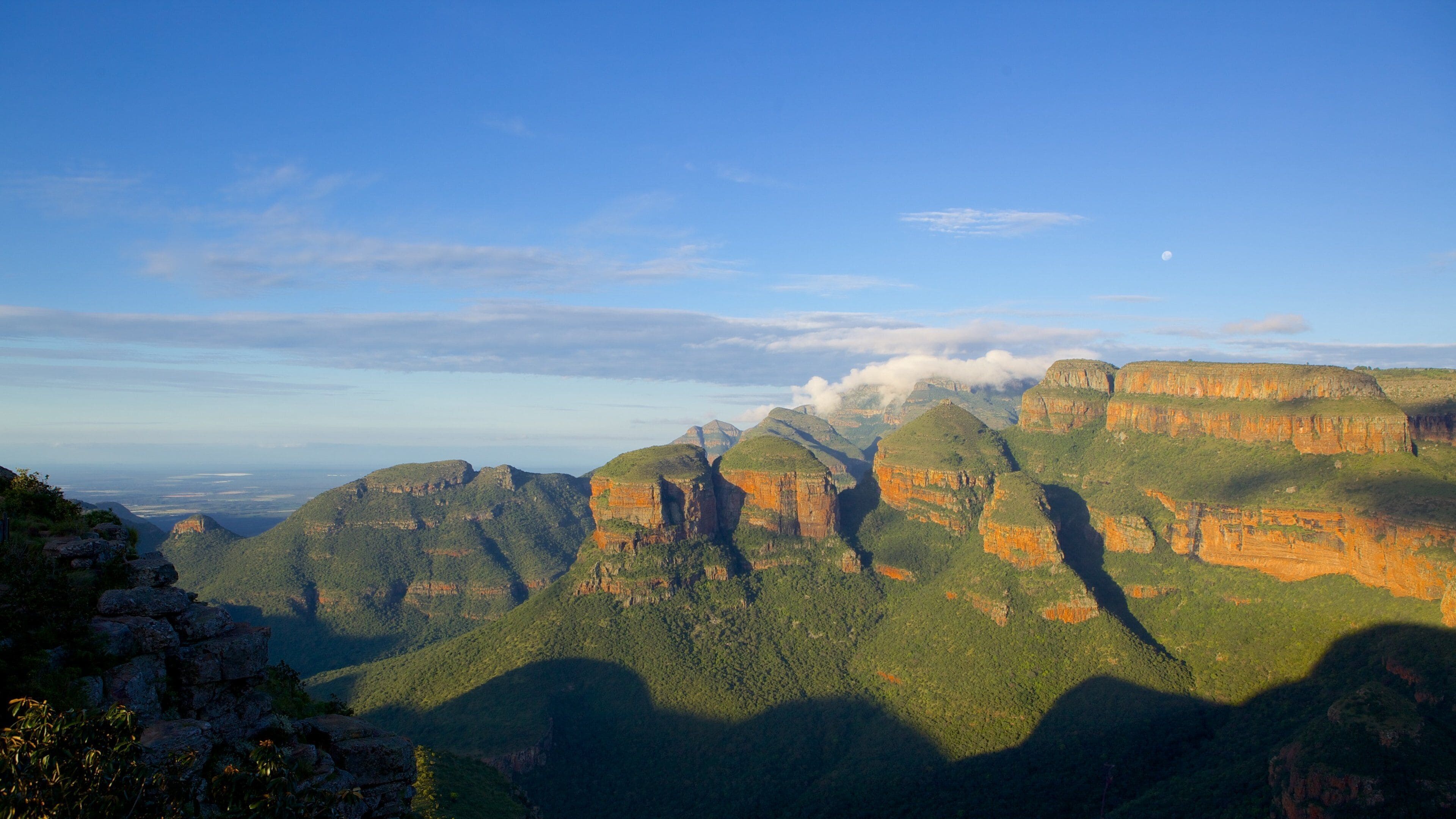 A mountainous landscape with layered rock formations and a clear sky.