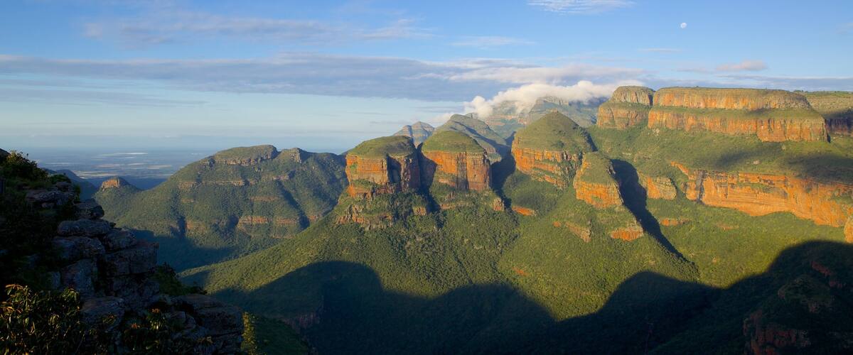 A mountainous landscape with layered rock formations and a clear sky.